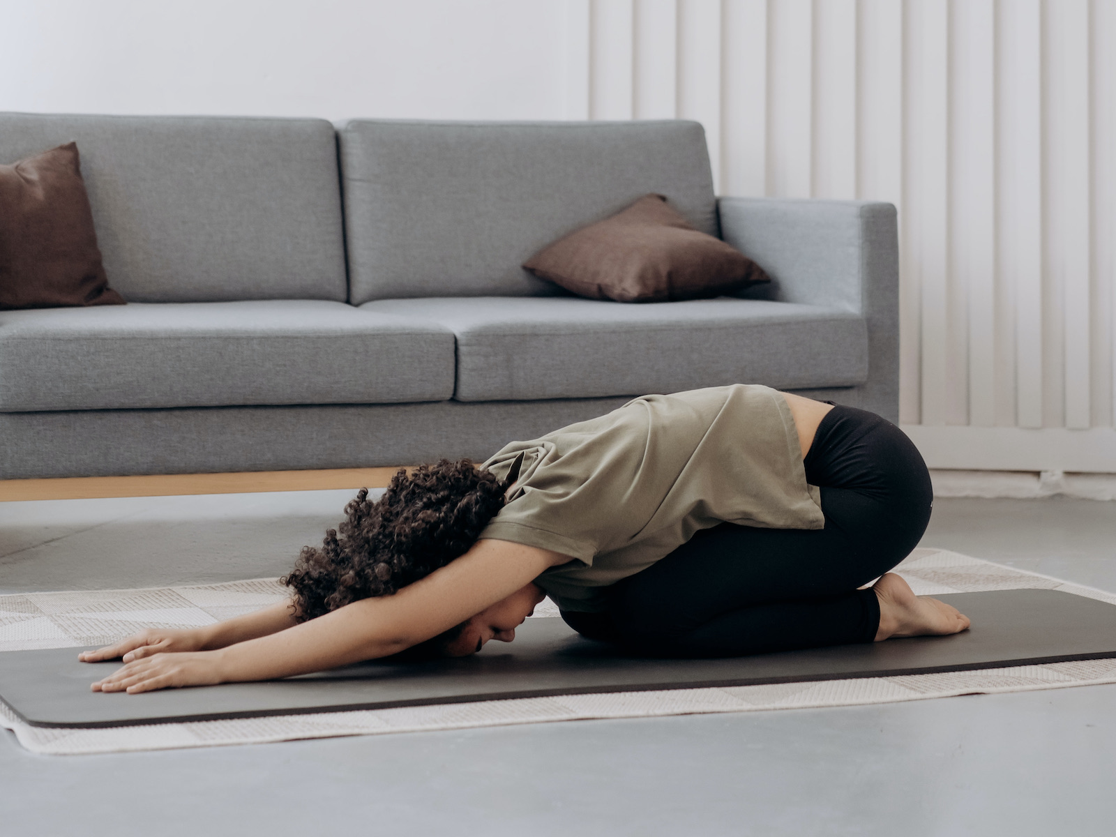 Frau macht Yoga vor Sofa